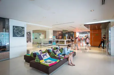 a woman sitting on a couch in a shopping mall at Trinity Silom Hotel in Bangkok