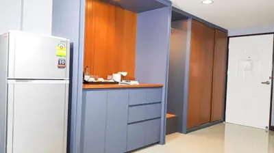 a kitchen with a white refrigerator and wooden cabinets at Room58 in Bangkok
