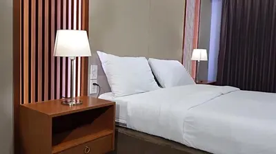 a bed in a hotel room with a night stand with a white bed at Room58 in Bangkok