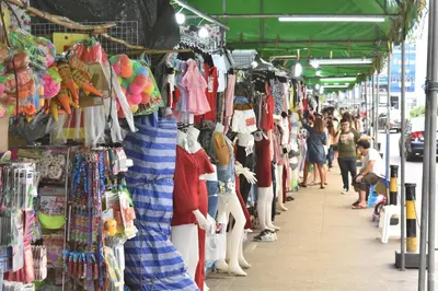 a crowd of people walking past a market with clothes on display at Hide Bangkok Hostel in Bangkok