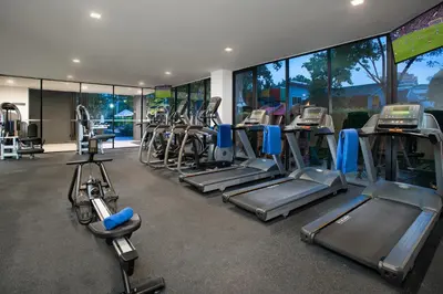 a gym with a row of treadmills and machines at Somerset Ekamai Bangkok in Bangkok