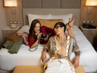 two women sitting on a bed taking a picture at SKYVIEW Hotel Bangkok - Sukhumvit in Bangkok
