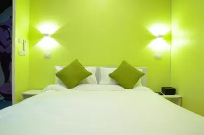 a bedroom with a large white bed with green walls at Maderla in Bangkok