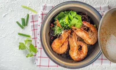 a bowl of food with shrimp and broccoli on a table at Maderla in Bangkok