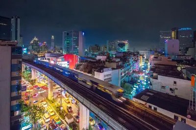 a train on a bridge over a city at night at 128 room and massage in Bangkok