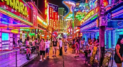 a crowd of people walking down a street with neon lights at 128 room and massage in Bangkok