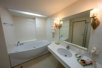 a bathroom with a tub and a sink and a mirror at Ariston Hotel Bangkok in Bangkok