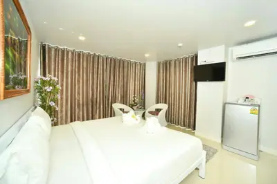 a bedroom with a white bed and two chairs at Parvena Hotel Sathorn in Bangkok