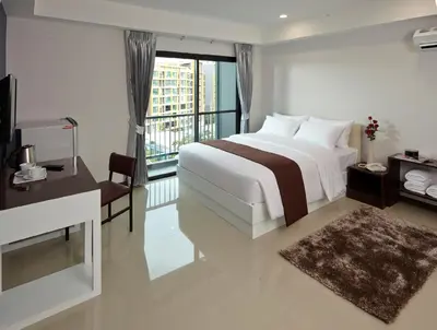 a white bedroom with a bed and a balcony at Casa Residence Hotel in Bangkok