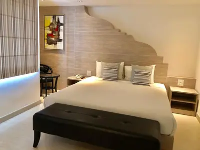 a bedroom with a large white bed and a staircase at Methavalai Residence Hotel in Bangkok