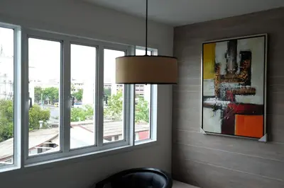 a room with windows and a chair and a picture at Methavalai Residence Hotel in Bangkok