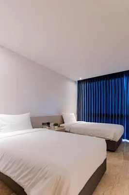 two beds in a hotel room with a window at Sukhothai Residence Ruam Ruedi in Bangkok