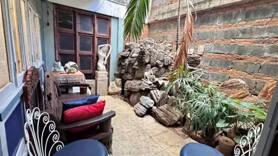 a balcony with chairs and a stone wall at Café de Baan Raow in Bangkok