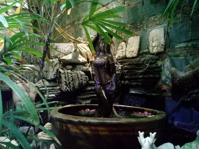 a statue of a girl in a pot in a garden at Café de Baan Raow in Bangkok