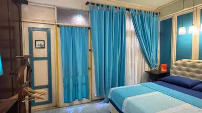 a bedroom with blue curtains and a bed and a window at Café de Baan Raow in Bangkok
