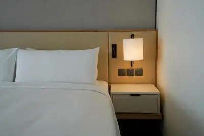 a bedroom with a white bed and a lamp at Marriott Executive Apartments Bangkok, Sukhumvit 50 in Bangkok