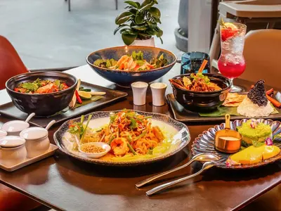 a table with plates of food and bowls of food at Marriott Executive Apartments Bangkok, Sukhumvit 50 in Bangkok