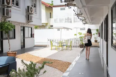 a woman walking down a corridor of a building at The President Hotel at Chokchai 4 in Bangkok