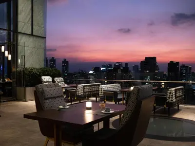 a table and chairs on a balcony with a city skyline at 137 Pillars Residences Bangkok in Bangkok