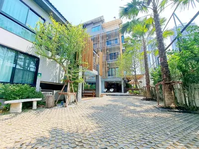 a cobblestone street in front of a building with palm trees at Nest by Sangob in Bangkok