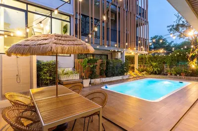 a table with an umbrella next to a swimming pool at Nest by Sangob in Bangkok