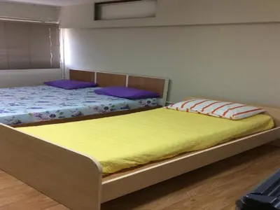 two beds in a bedroom with yellow sheets and purple pillows at IMPACT Challenger Muang Thong Thani Service Apartment in Bangkok