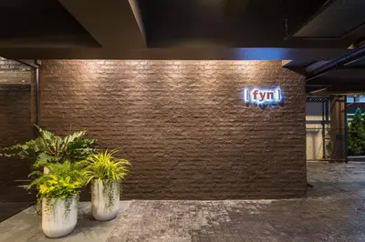 a brick wall with two potted plants and a neon sign at Fyn Hotel in Bangkok