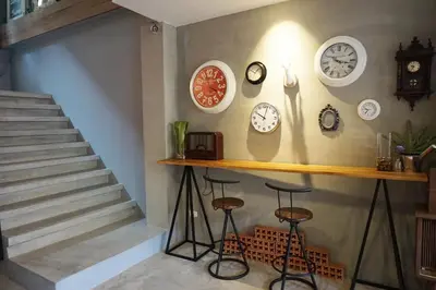 a room with clocks on the wall and two stools at Hansa Bangkok House in Bangkok