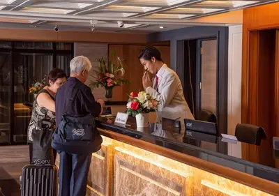 a man standing at a counter in a hotel lobby at Dang Derm In The Park Khaosan in Bangkok