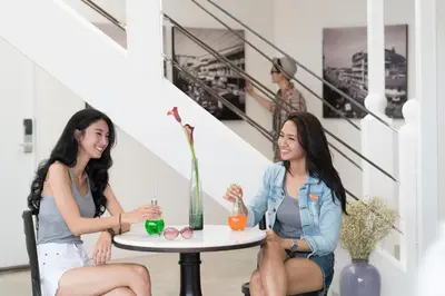 two women sitting at a table with drinks at Cacha Bed in Bangkok