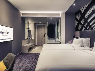 a hotel room with two beds and a mirror at Mercure Bangkok Makkasan in Bangkok