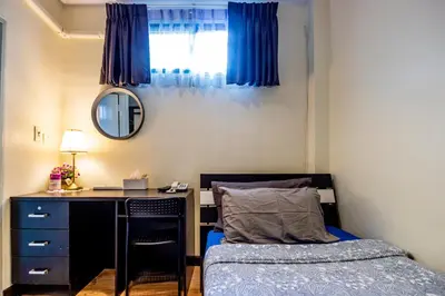 a bedroom with a desk and a bed with blue curtains at The Cube Sathorn Boutique Hotel เดอะ คิวบ์ สาทร บูติค โฮเทล Near BTS Surasak in Bangkok