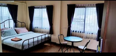 a bedroom with a bed and a table and windows at The Cube Sathorn Boutique Hotel เดอะ คิวบ์ สาทร บูติค โฮเทล Near BTS Surasak in Bangkok