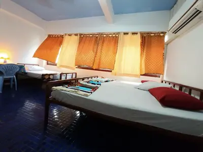 a bedroom with two beds and a table with a chair at Prasuri Guest House in Bangkok