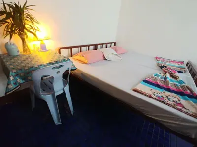 a bed with a night stand next to a desk at Prasuri Guest House in Bangkok