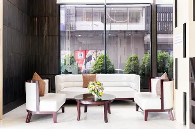 a living room with white furniture and a table and chairs at Grand Ratchapruek Hotel in Ban Bang Phlap