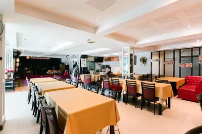 a restaurant with tables and chairs and a red couch at Grand Ratchapruek Hotel in Ban Bang Phlap