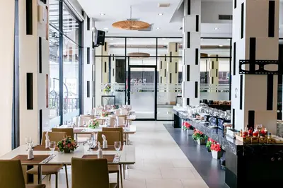 a restaurant with tables and chairs and windows at Grand Ratchapruek Hotel in Ban Bang Phlap