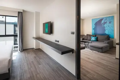 a living room with a couch and a table on a wall at Cross Vibe Bangkok Sukhumvit in Bangkok