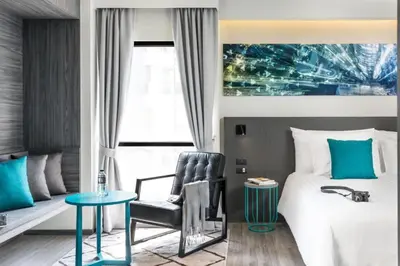 a bedroom with a bed and a chair and a table at Cross Vibe Bangkok Sukhumvit in Bangkok
