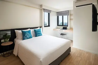 a bedroom with a large white bed with blue pillows at Cross Vibe Bangkok Sukhumvit in Bangkok