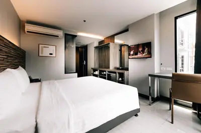 a bedroom with a large white bed and a desk at Spenza Hotel in Bangkok