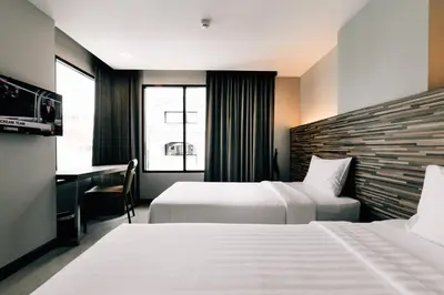 a hotel room with two beds and a desk at Spenza Hotel in Bangkok