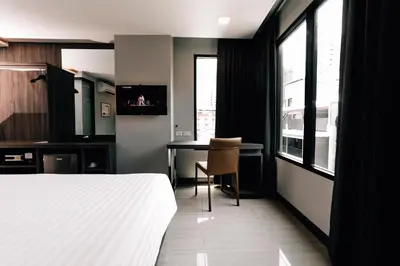 a bedroom with a bed and a desk and a table at Spenza Hotel in Bangkok