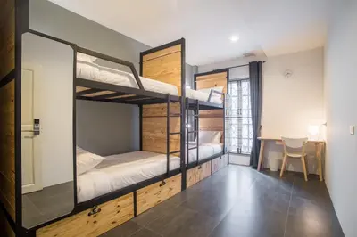 a room with three bunk beds and a table at X9Hostel in Bangkok