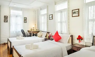 two beds in a room with white walls and windows at Baankachitpan Bangkok Hotel in Bangkok