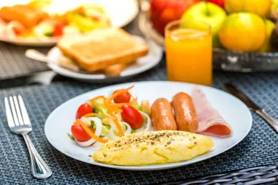 a table with plates of breakfast food on it at Baankachitpan Bangkok Hotel in Bangkok