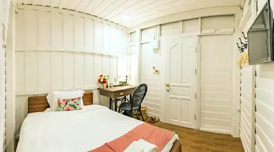 a bedroom with a bed and a desk in it at Baankachitpan Bangkok Hotel in Bangkok