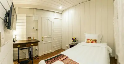 a bedroom with a bed and a desk and a door at Baankachitpan Bangkok Hotel in Bangkok