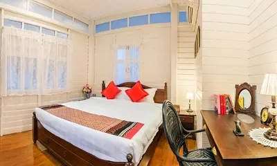 a bedroom with a bed and a table and a desk at Baankachitpan Bangkok Hotel in Bangkok